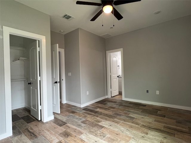 unfurnished bedroom featuring hardwood / wood-style floors, ceiling fan, a walk in closet, and a closet