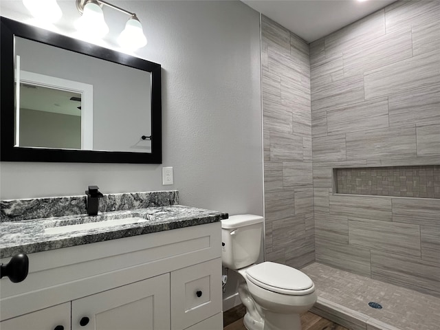 bathroom featuring toilet, vanity, and tiled shower