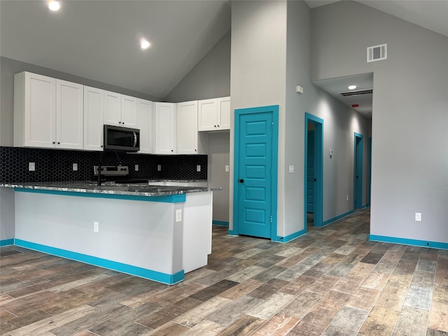 kitchen with high vaulted ceiling, dark wood-type flooring, appliances with stainless steel finishes, and white cabinets