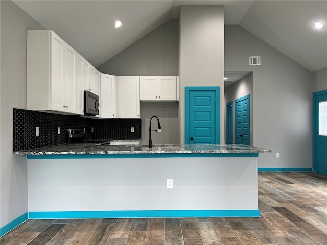 kitchen featuring white cabinetry, stainless steel range, dark wood-type flooring, and kitchen peninsula