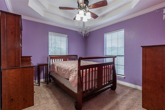 bedroom featuring crown molding, a tray ceiling, carpet floors, ceiling fan, and multiple windows