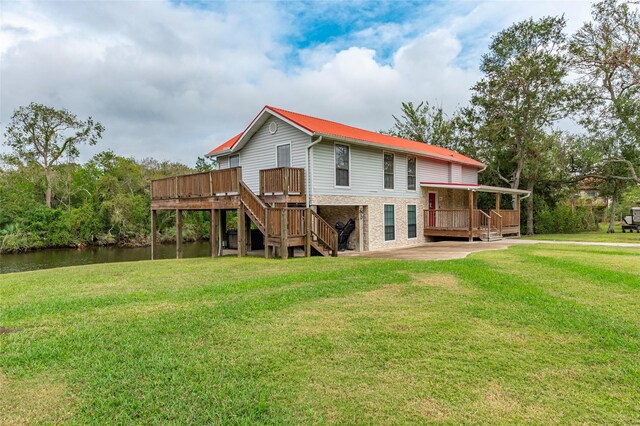 rear view of property featuring a yard and a deck with water view