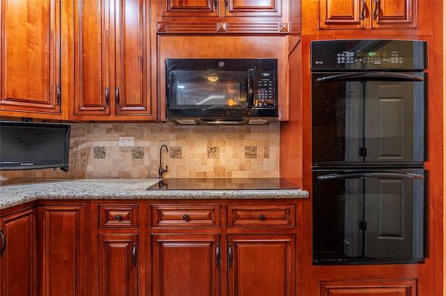 kitchen featuring black appliances, decorative backsplash, and light stone counters