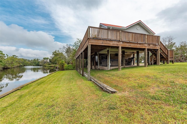 rear view of property featuring a deck with water view and a yard