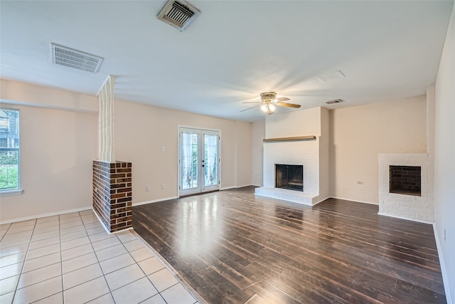 unfurnished living room featuring ceiling fan, light hardwood / wood-style floors, a fireplace, and french doors