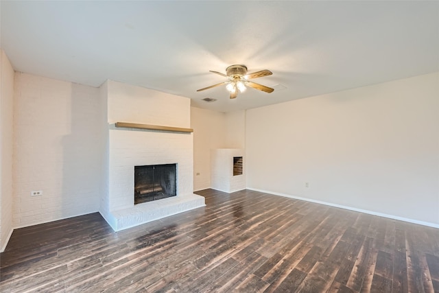 unfurnished living room with ceiling fan, dark hardwood / wood-style flooring, and a brick fireplace