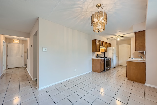 kitchen featuring gas range, ceiling fan with notable chandelier, sink, decorative light fixtures, and white fridge