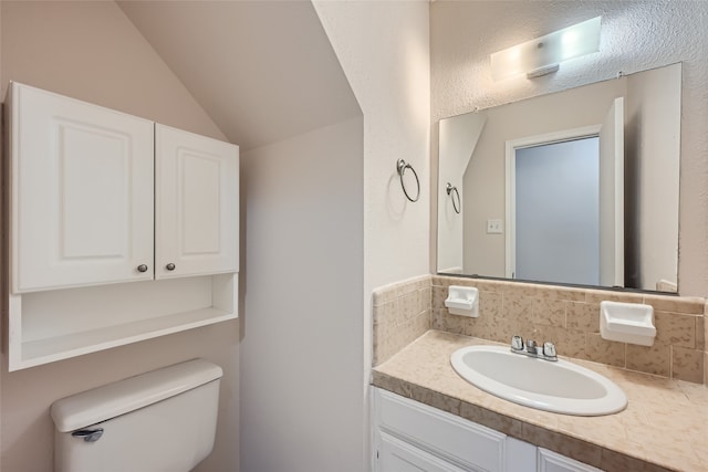 bathroom featuring vanity, toilet, and lofted ceiling