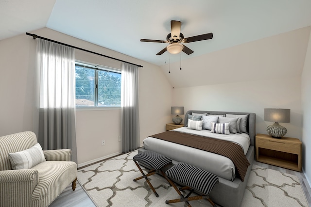 bedroom with ceiling fan, light hardwood / wood-style floors, and vaulted ceiling