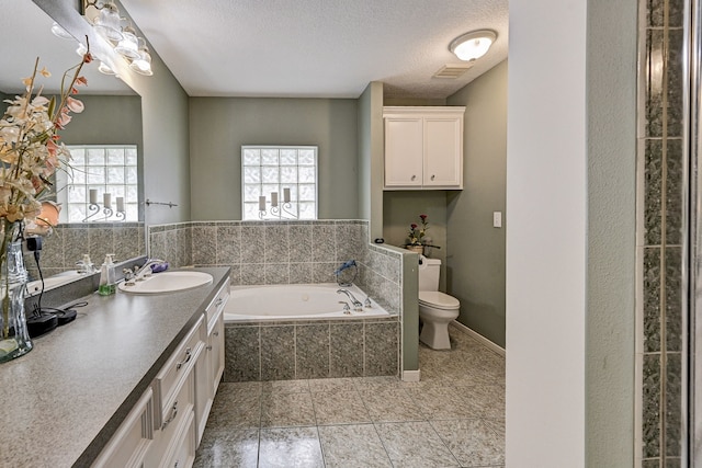 bathroom with vanity, toilet, a textured ceiling, and a wealth of natural light