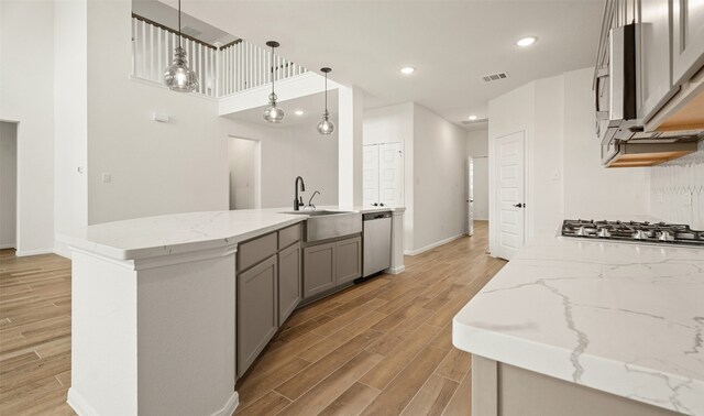 kitchen featuring light hardwood / wood-style flooring, sink, gray cabinets, appliances with stainless steel finishes, and decorative light fixtures