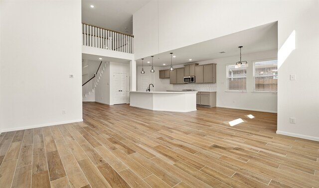 unfurnished living room with a towering ceiling and light wood-type flooring