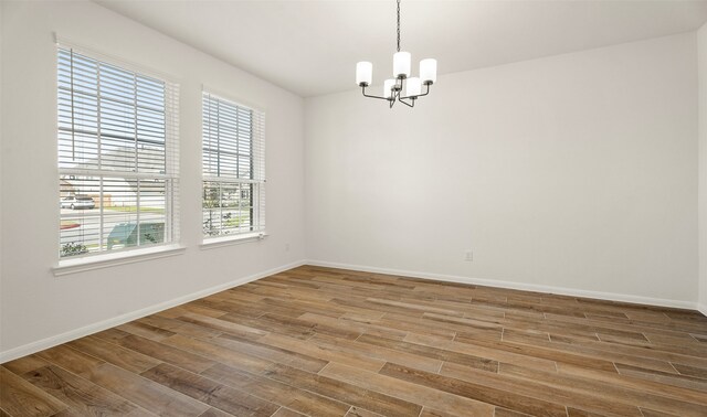 empty room with an inviting chandelier and hardwood / wood-style flooring