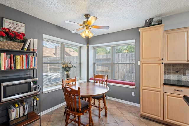 tiled dining space with a textured ceiling and ceiling fan