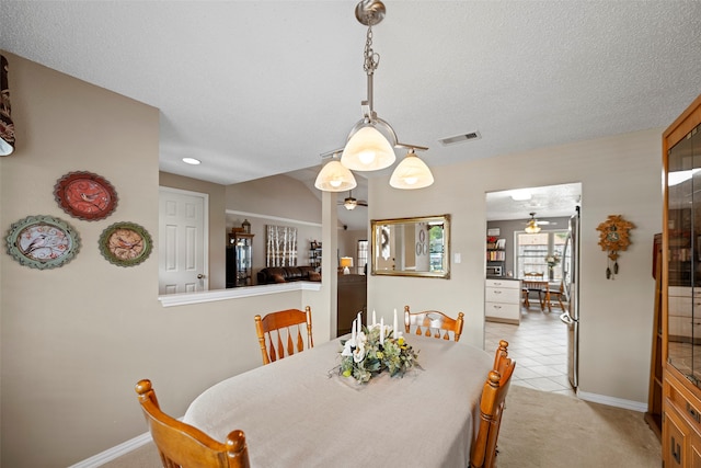 carpeted dining area with a textured ceiling and ceiling fan