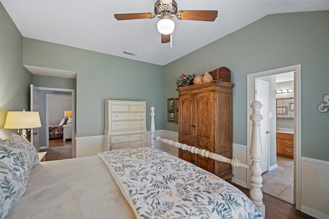 bedroom with ensuite bathroom, light hardwood / wood-style flooring, ceiling fan, and vaulted ceiling