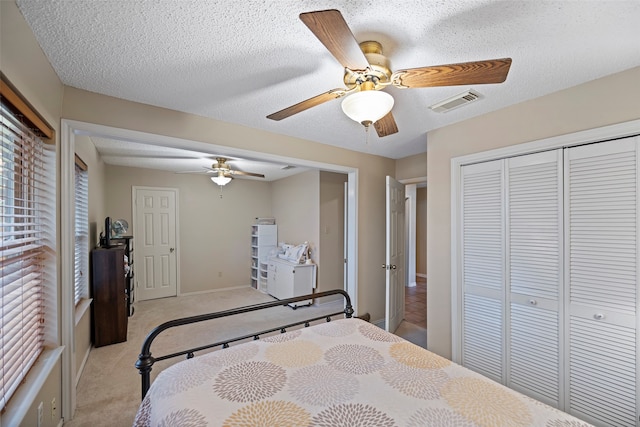 carpeted bedroom with a closet, a textured ceiling, and ceiling fan