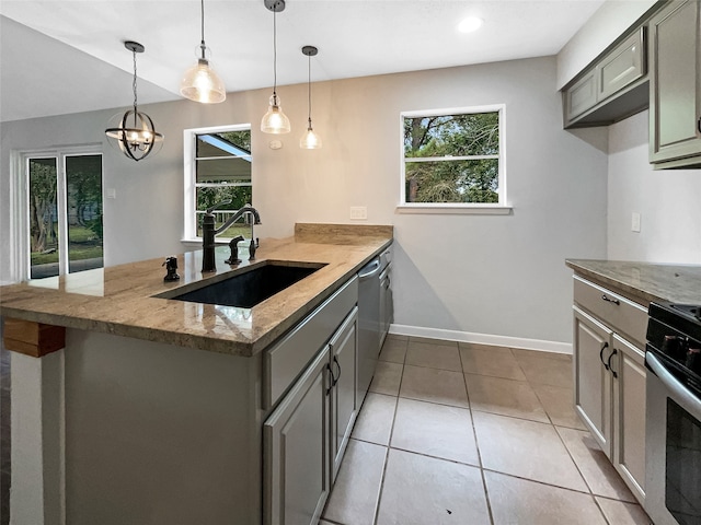 kitchen with kitchen peninsula, appliances with stainless steel finishes, sink, and light stone counters