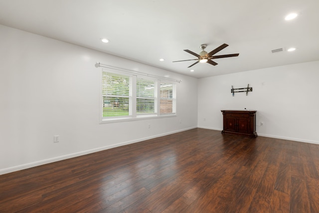 empty room featuring a barn door, ceiling fan, and dark hardwood / wood-style flooring