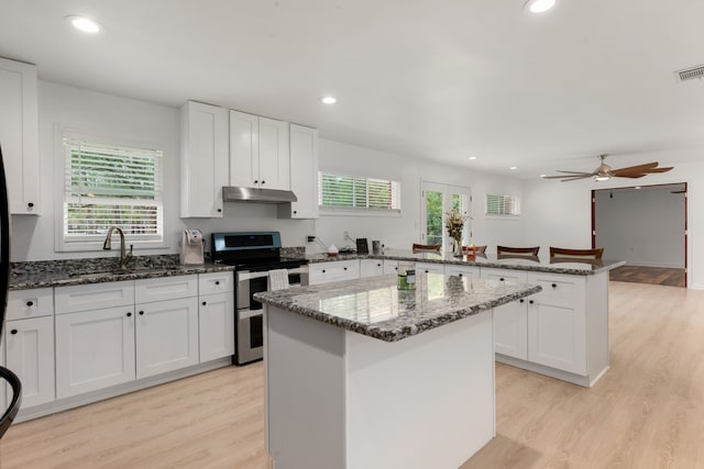 kitchen featuring white cabinets, light hardwood / wood-style flooring, a kitchen island, and electric range