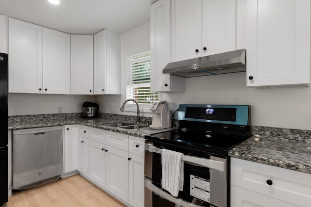 kitchen with white cabinets, appliances with stainless steel finishes, dark stone counters, and sink