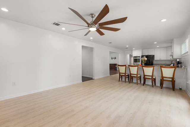 living room with ceiling fan and light hardwood / wood-style floors