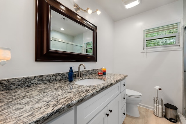 bathroom with toilet, vanity, hardwood / wood-style floors, and a shower with door