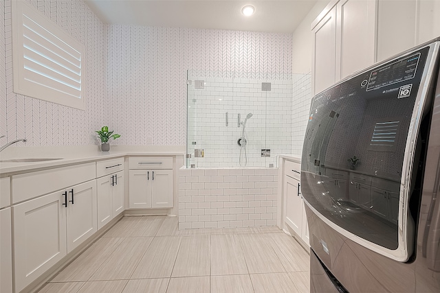 full bathroom featuring wallpapered walls, a shower stall, a sink, and tile patterned floors