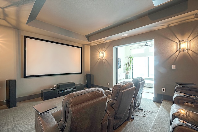 home theater room with light colored carpet and a tray ceiling