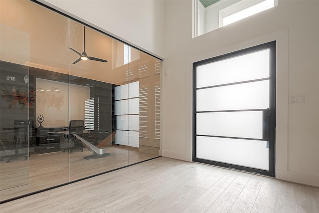 entryway featuring light wood-style floors, ceiling fan, and a high ceiling