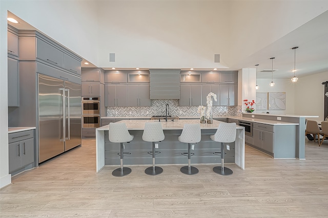 kitchen featuring a kitchen island with sink, appliances with stainless steel finishes, light countertops, and gray cabinetry