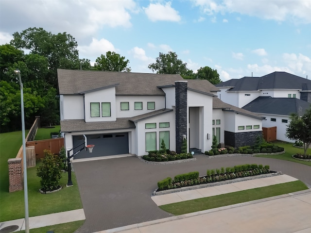 view of front of property with decorative driveway, roof with shingles, stucco siding, an attached garage, and fence