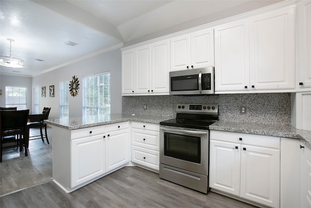 kitchen with kitchen peninsula, white cabinets, appliances with stainless steel finishes, and ornamental molding