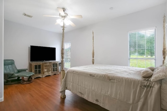 bedroom with ceiling fan, wood-type flooring, and multiple windows