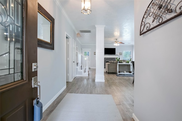 foyer with ornamental molding, ceiling fan, ornate columns, and light wood-type flooring