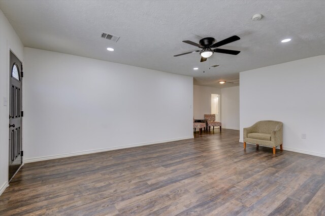 living area with dark wood-type flooring, a textured ceiling, and ceiling fan