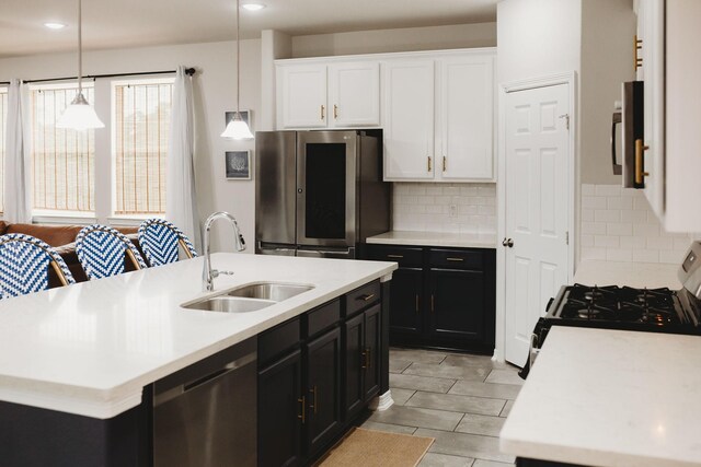 kitchen featuring a kitchen island with sink, sink, decorative light fixtures, and appliances with stainless steel finishes