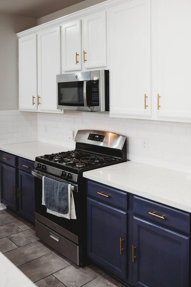 kitchen with blue cabinetry, decorative backsplash, white cabinetry, and stainless steel appliances