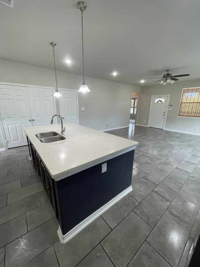 kitchen featuring pendant lighting, a center island with sink, ceiling fan, and sink