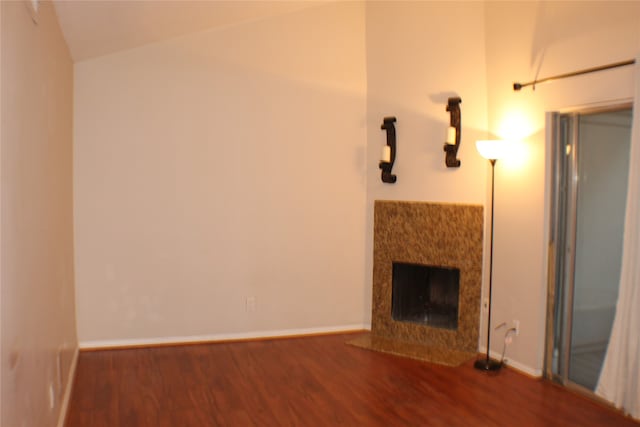 unfurnished living room featuring dark wood-type flooring, a premium fireplace, and lofted ceiling