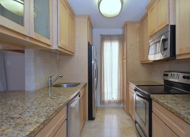 kitchen with stainless steel appliances, light stone counters, sink, backsplash, and light brown cabinetry