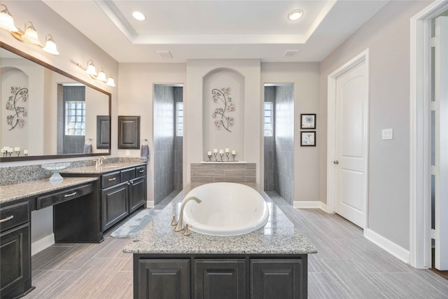 bathroom featuring a bathtub, vanity, and a raised ceiling