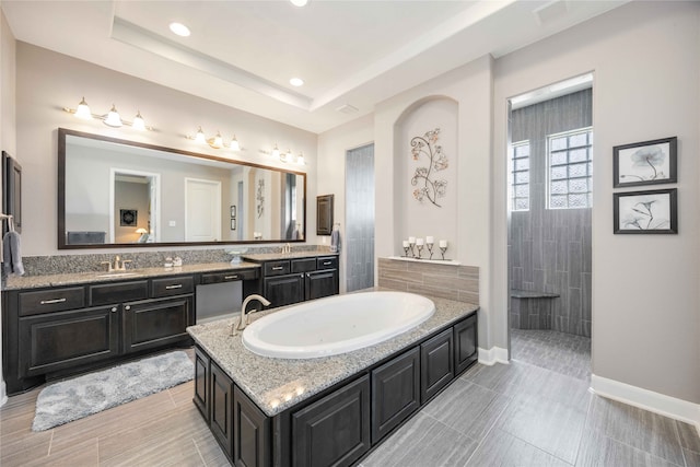 bathroom with a tray ceiling, plus walk in shower, and vanity