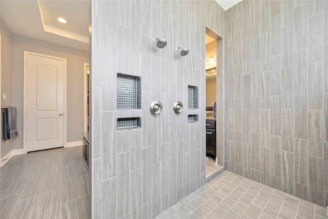 bathroom with vanity, a raised ceiling, and a tile shower