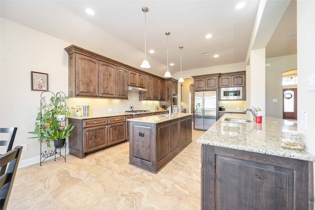 kitchen with stainless steel appliances, a center island with sink, sink, tasteful backsplash, and pendant lighting