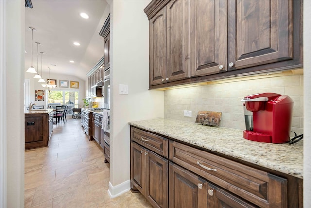 kitchen featuring sink, tasteful backsplash, light stone countertops, decorative light fixtures, and lofted ceiling