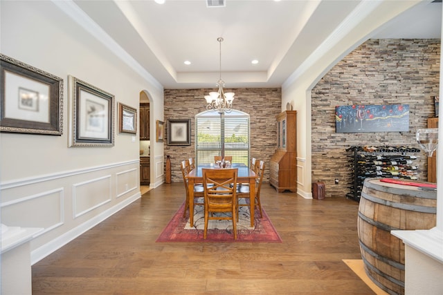 dining area featuring wood-type flooring, a raised ceiling, and an inviting chandelier