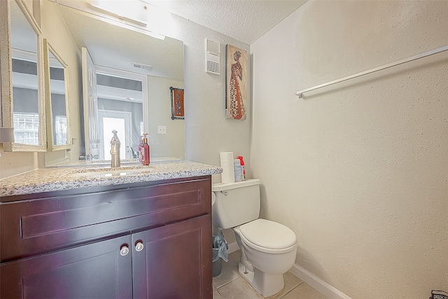 bathroom with tile patterned flooring, vanity, a textured ceiling, and toilet