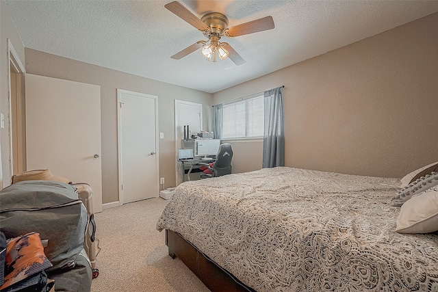 bedroom featuring a textured ceiling, light colored carpet, and ceiling fan