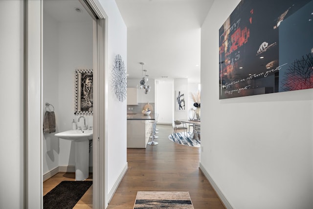 corridor featuring wood-type flooring and sink